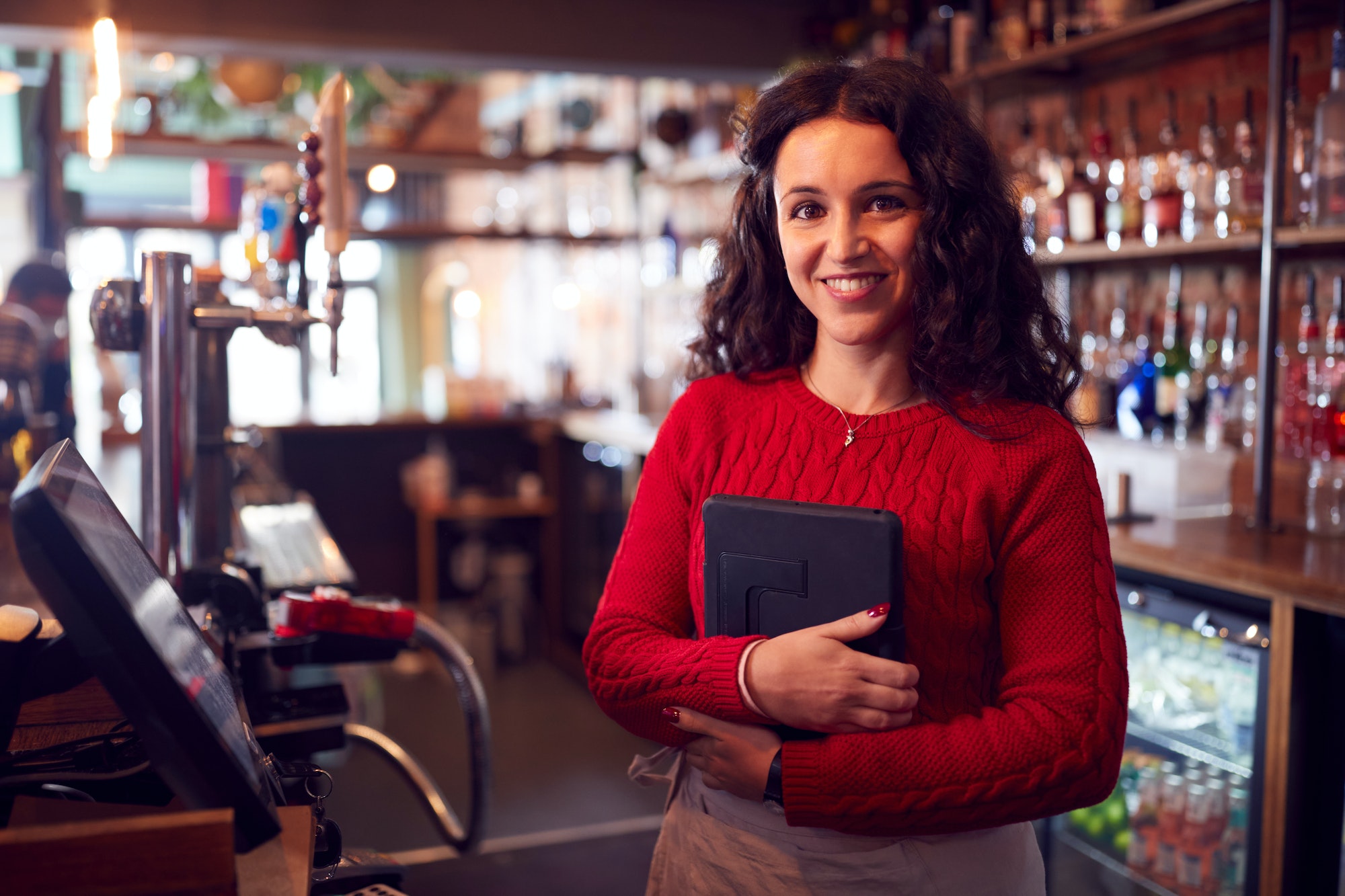 Portrait Of Smiling Female Bar Owner With Digital Tablet Standing Behind Counter
